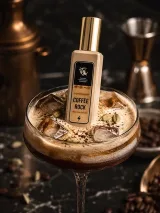 Натюрморт при контрастному світлі: флакон Coffee Rock, керамічна піала зі свіжемеленою арабікою, поряд зелені кавові зерна, коробочки кардамону і фрагмент темного дерева на графітовому камені