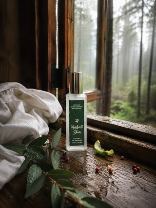 Долоня з флаконом Herbal Skin на тлі лляної тканини холодного відтінку — близький деревно-тілесний шлейф ефекту другої шкіри